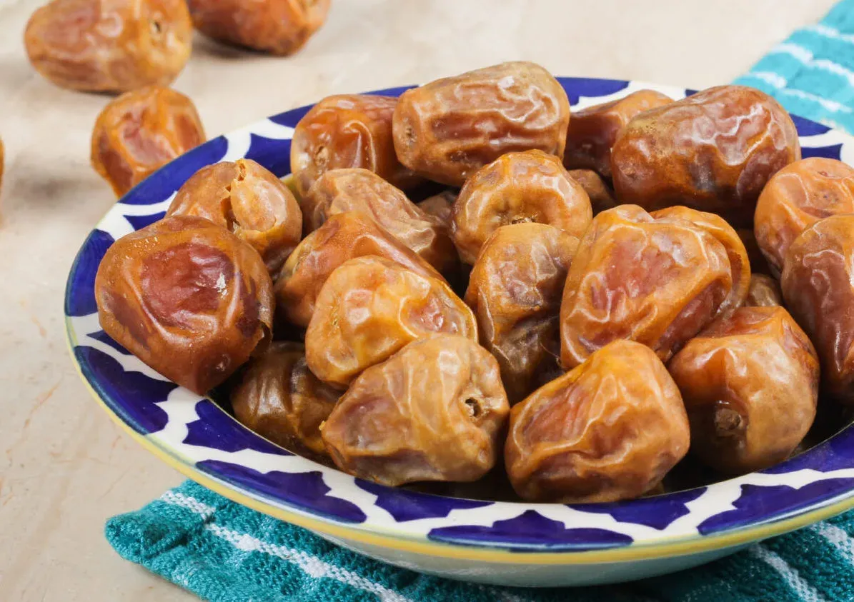 Kurma Sukkari berwarna kecokelatan di dalam sebuah mangkok berwarna biru dan putih