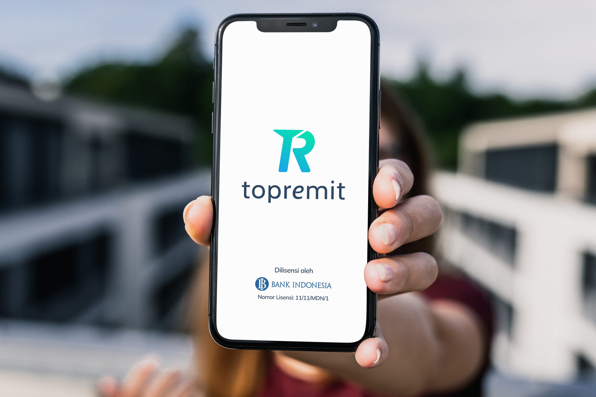 Seorang wanita menunjukkan ponsel yang menampilkan aplikasi Topremit di layar