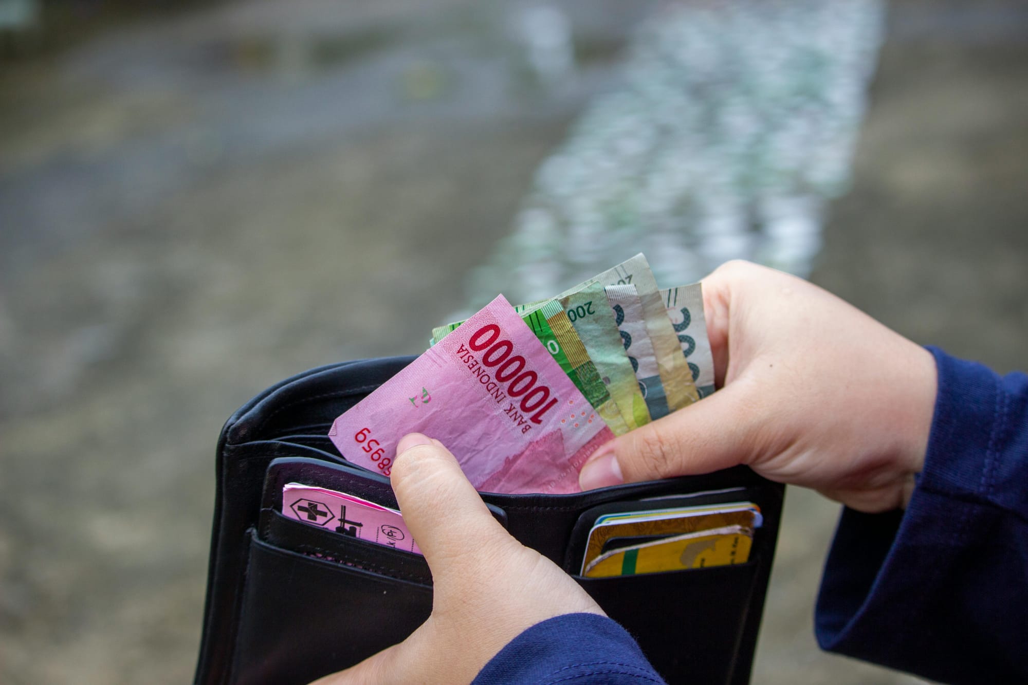 A person holding Indonesian rupiah in a wallet