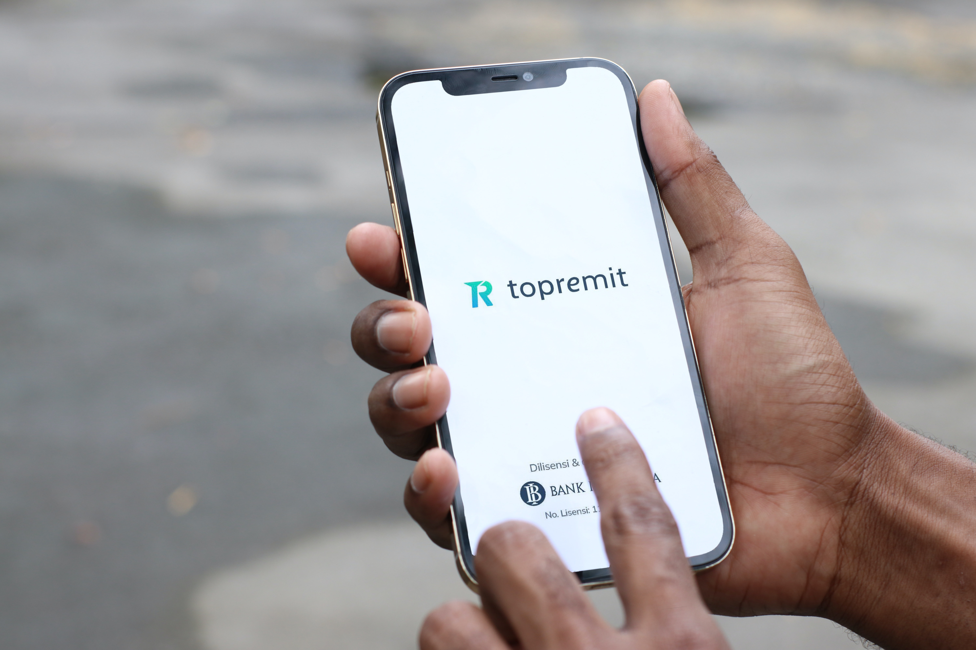 Seseorang menggunakan aplikasi Topremit di ponsel untuk melakukan transfer tanpa biaya admin ke berbagai bank di Indonesia.