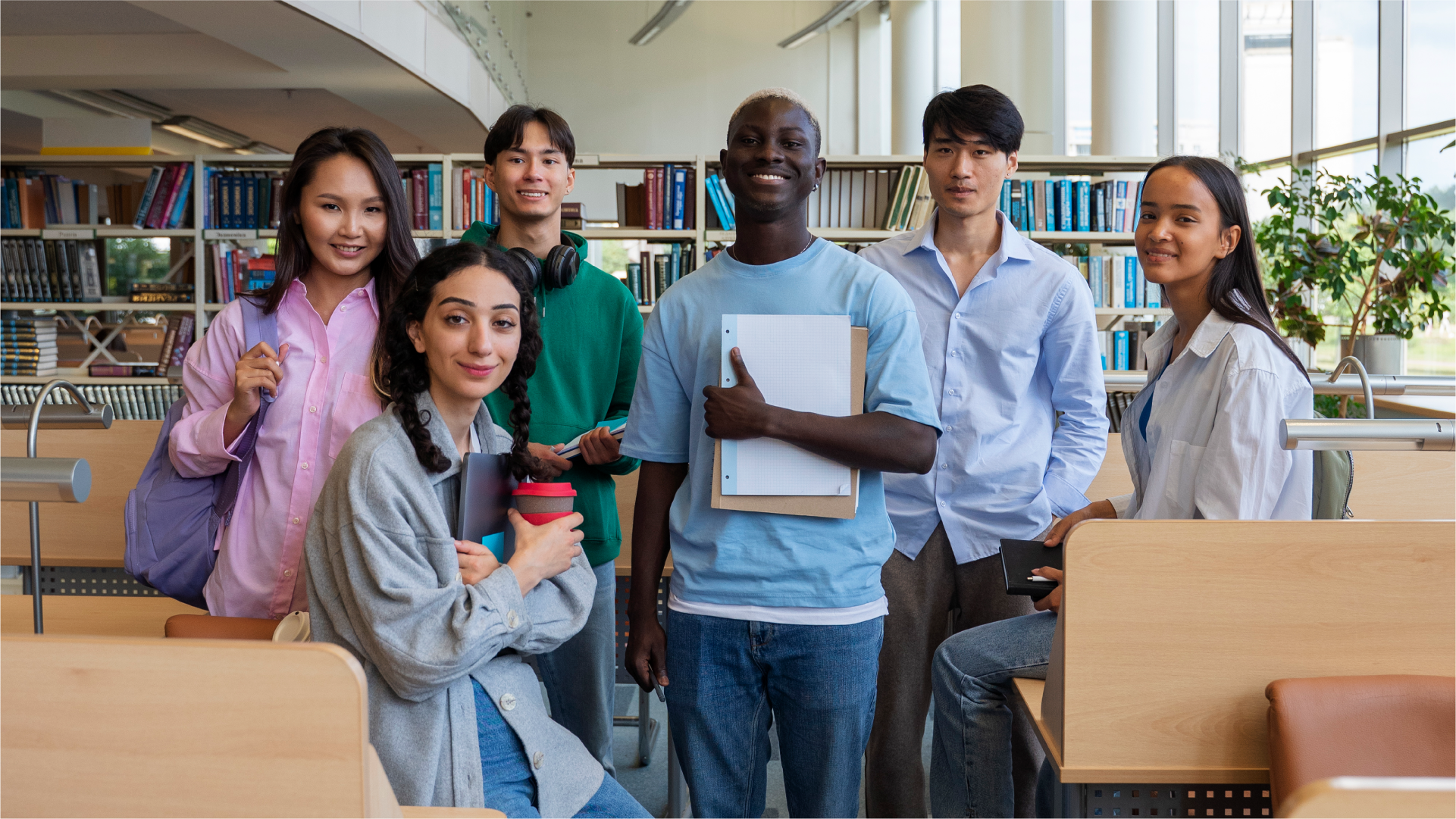 Sekelompok mahasiswa di perpustakaan dengan buku dan laptop, melambangkan investasi pada pendidikan sebagai bagian dari peningkatan kualitas sumber daya manusia.