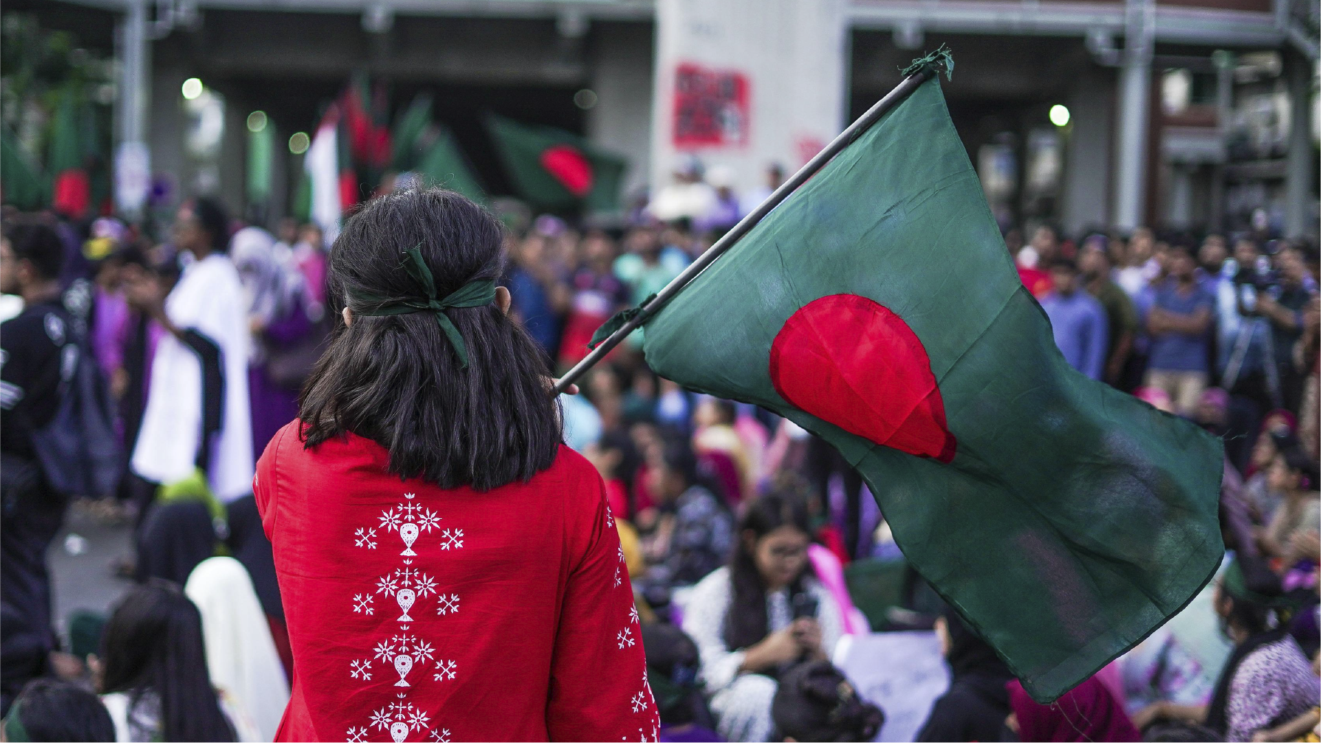 Seseorang membawa bendera Bangladesh di tengah keramaian sebagai ilustrasi arus remitansi dari pekerja migran.