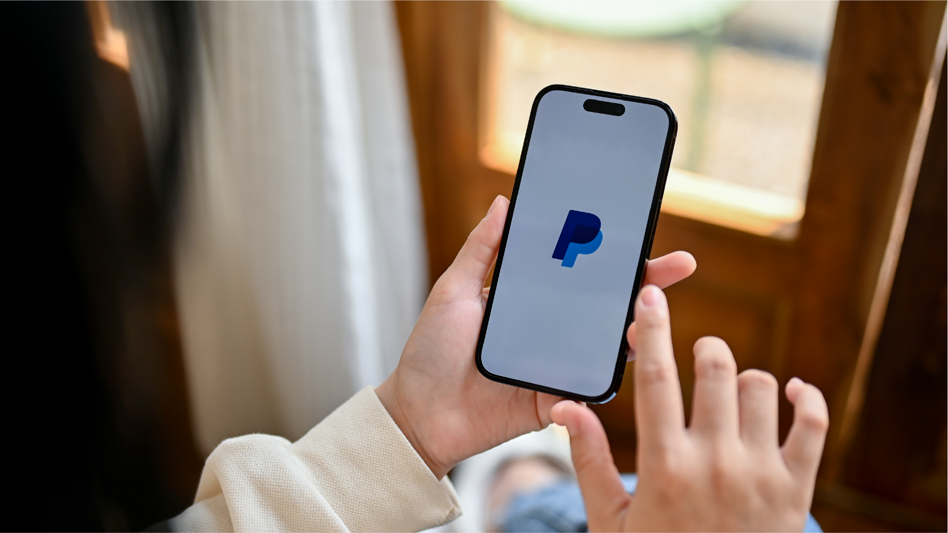 Logo PayPal di smartphone sebagai ilustrasi e-wallet untuk transaksi internasional secara online.