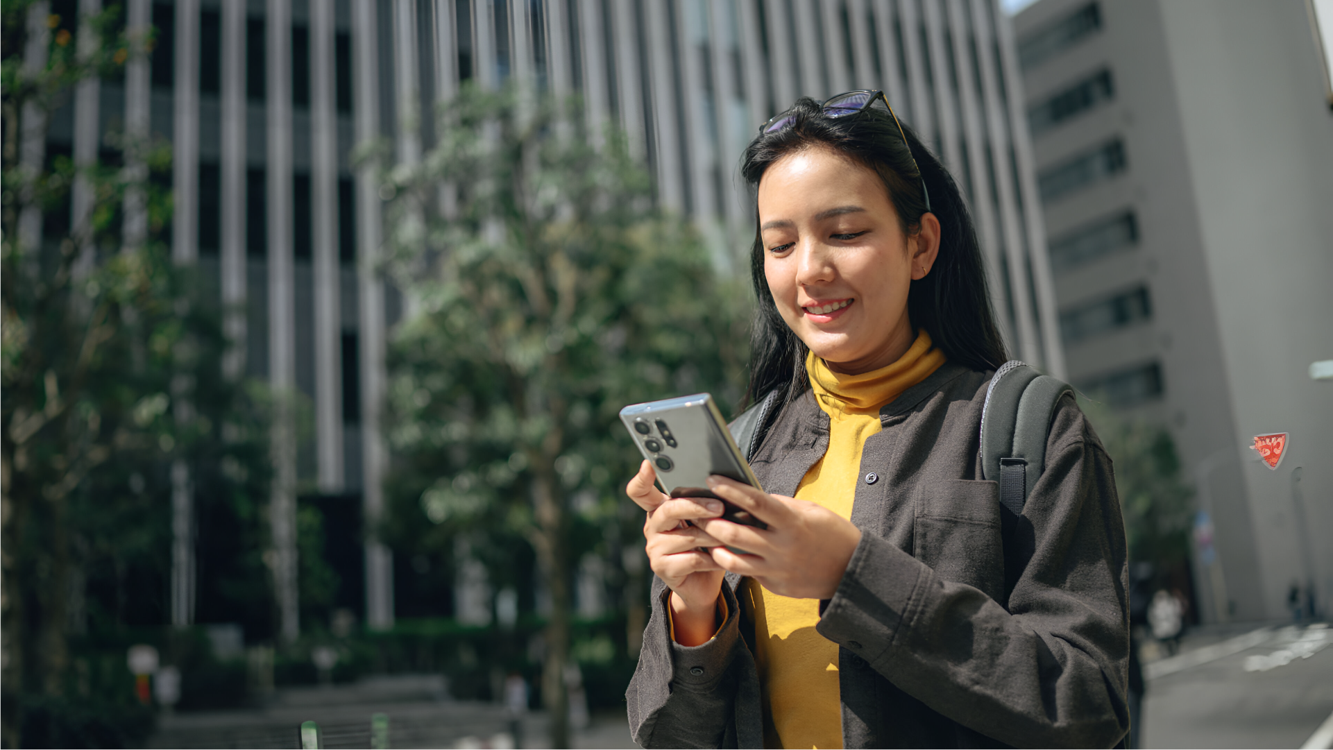 Perempuan menggunakan ponsel di area perkantoran untuk mengirim uang ke Filipina dengan layanan digital.