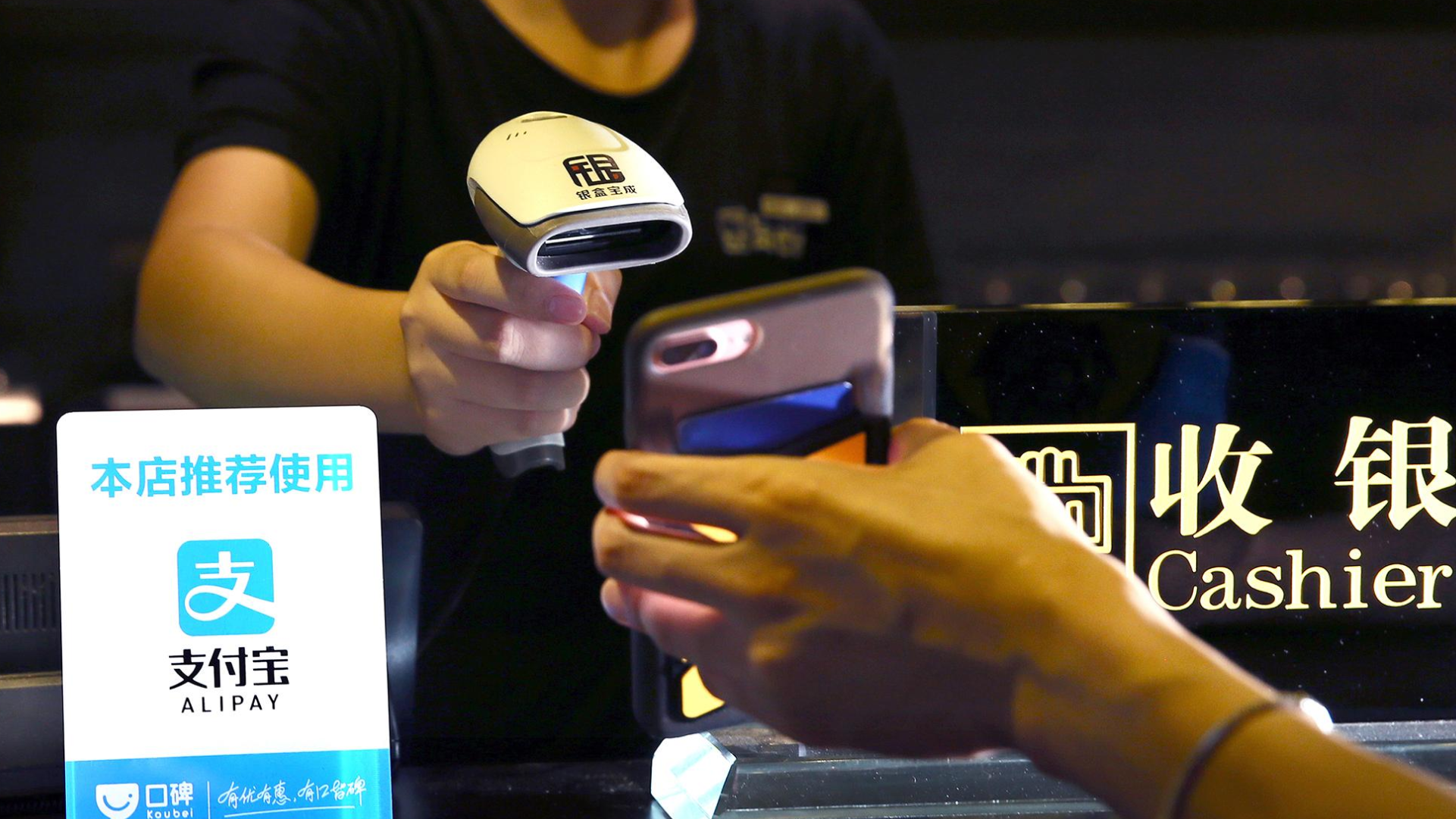 Pelanggan menggunakan Alipay melalui ponsel saat melakukan pembayaran cashless di kasir
