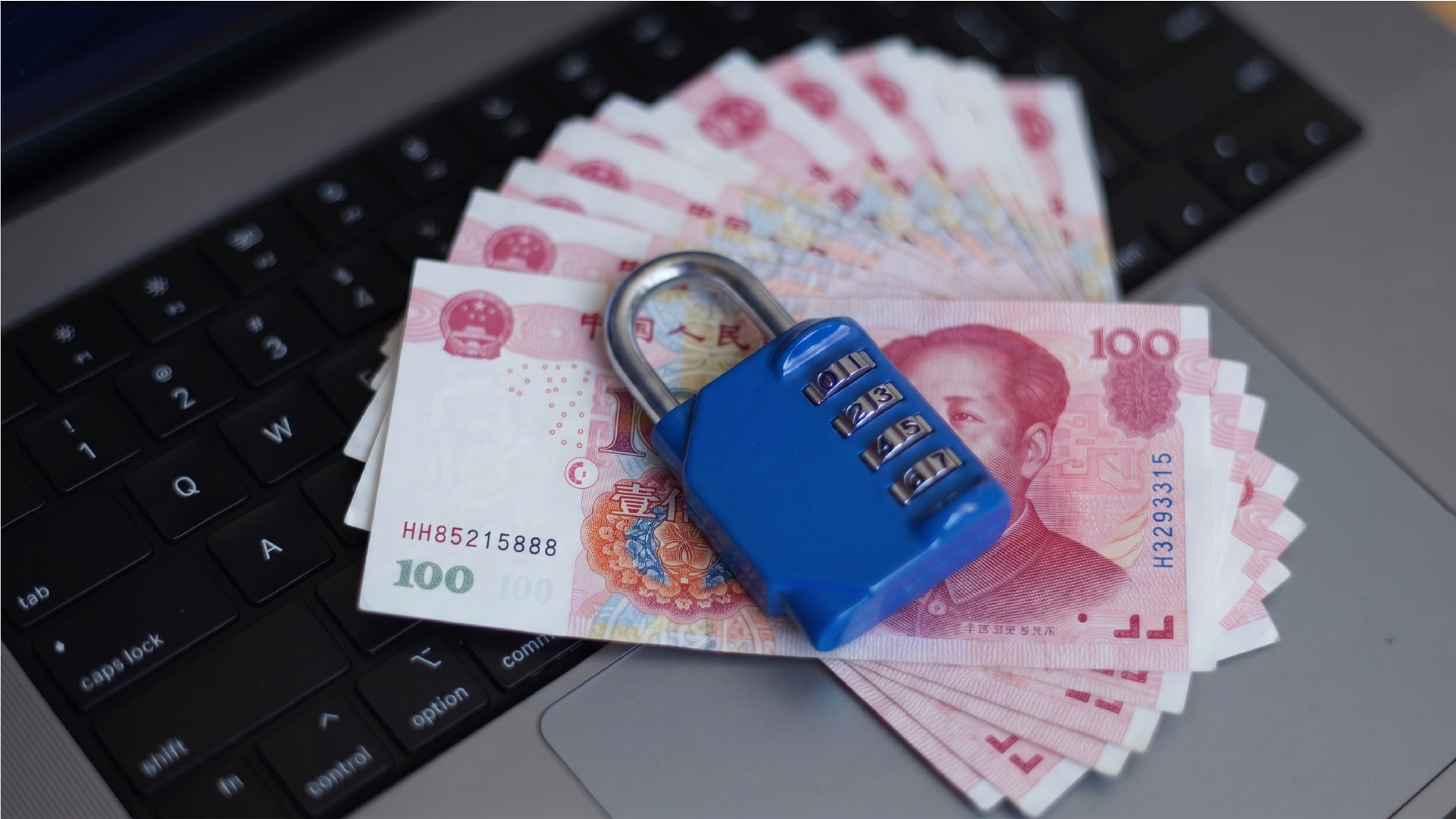 人民币现金放在笔记本电脑上并由密码锁保护，象征安全汇款到中国