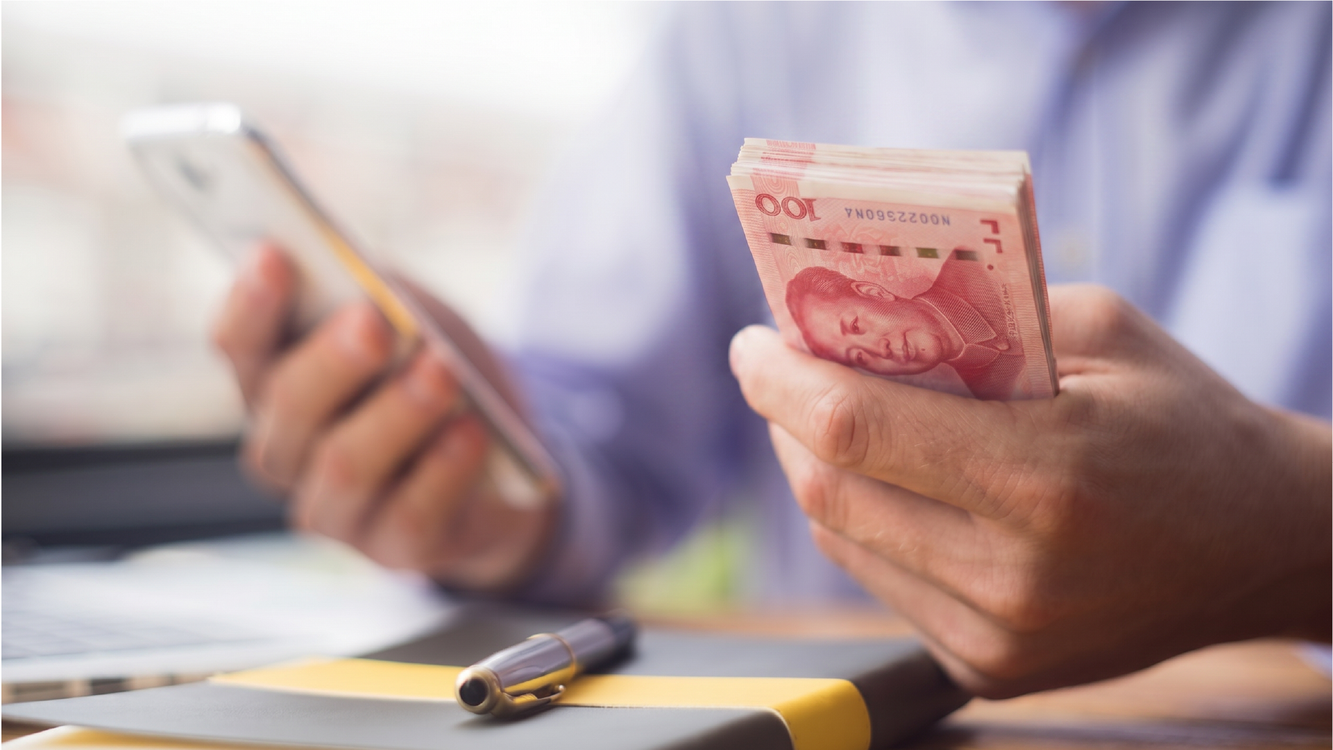 用户手持人民币并使用手机处理从印尼汇款到中国的交易