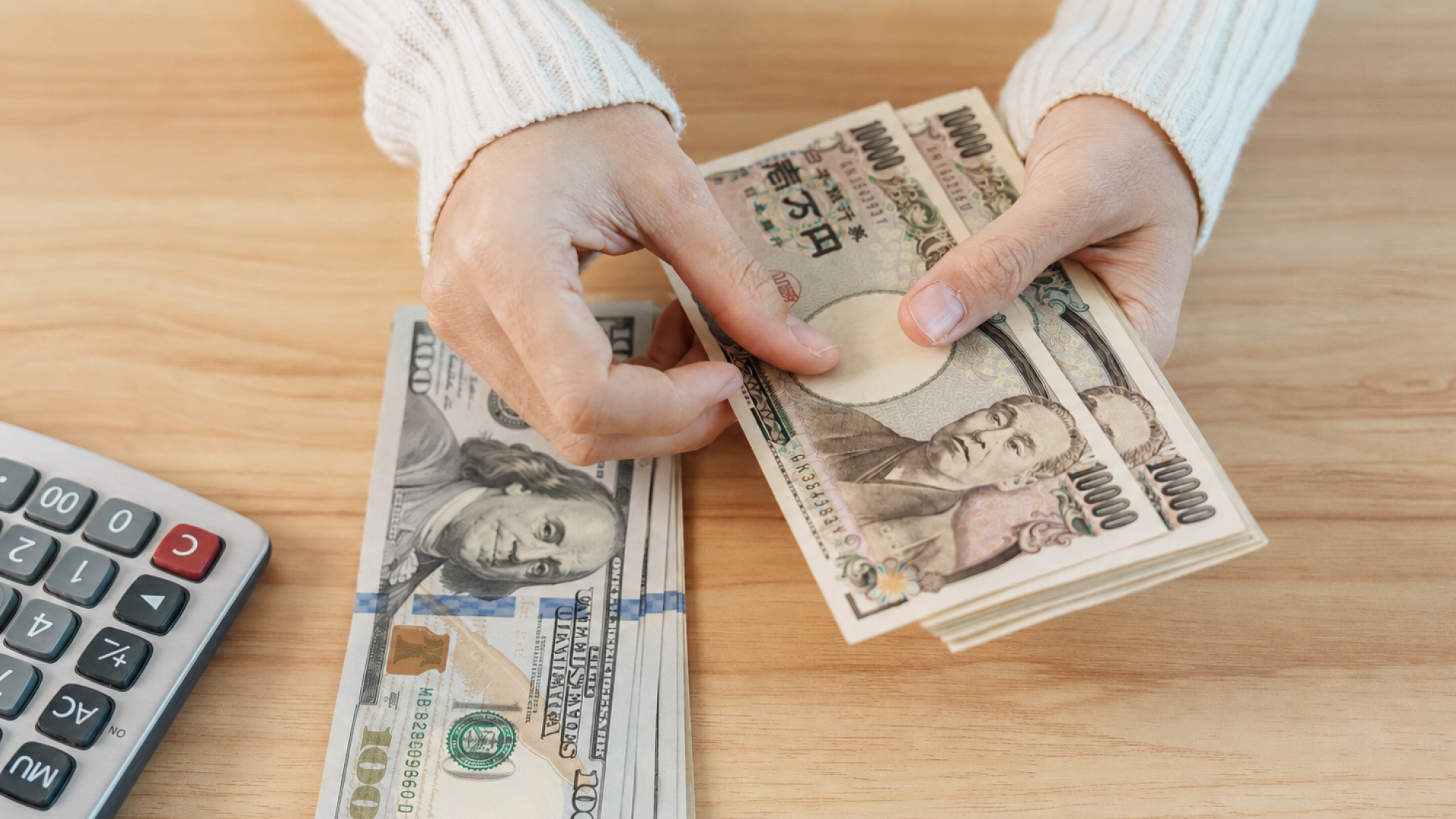 日本円と米ドルの紙幣を確認する様子。日本への海外送金で通貨や受取額を確認するイメージ
