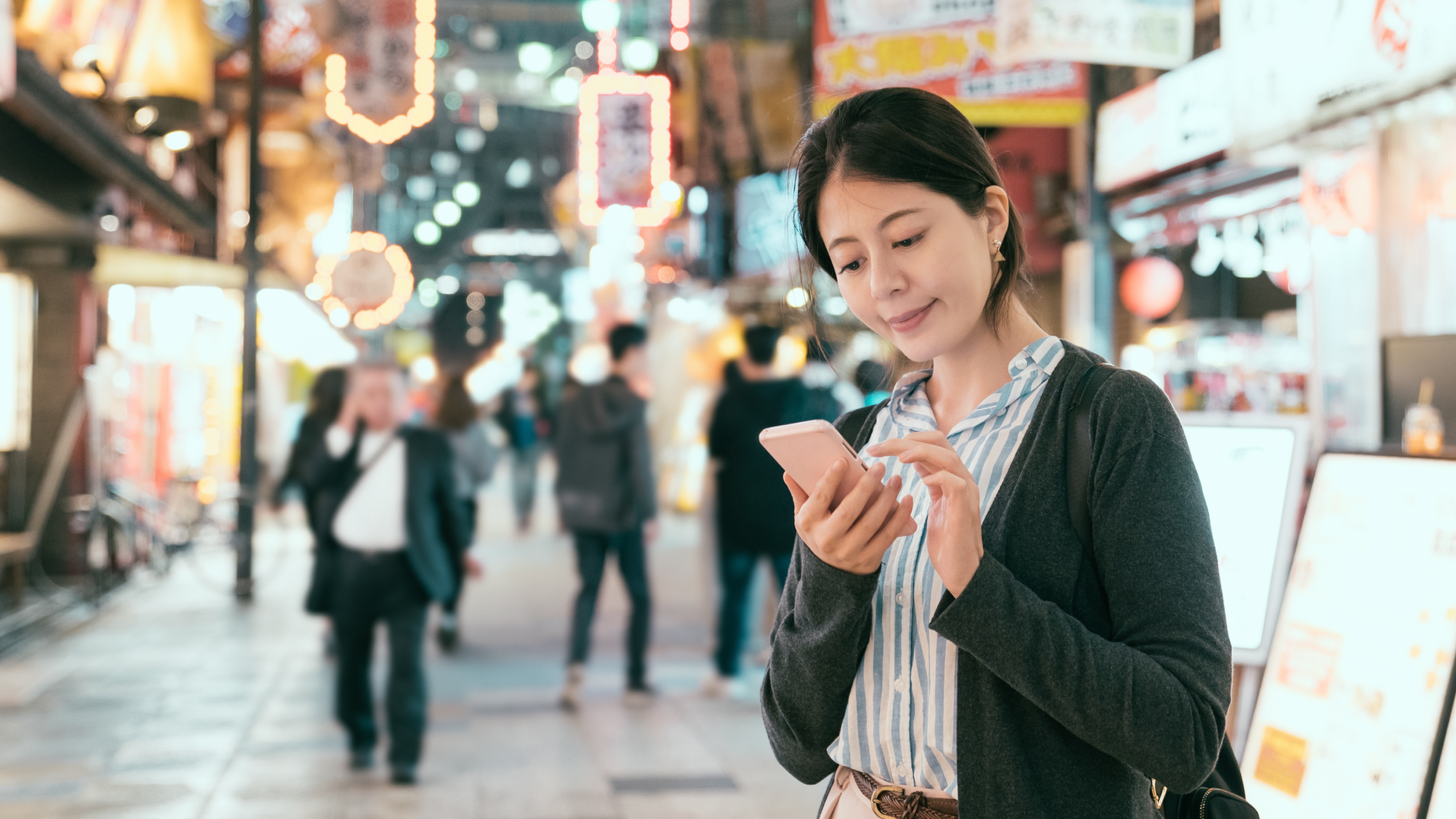 日本の街中でスマートフォンを使って海外送金をする女性