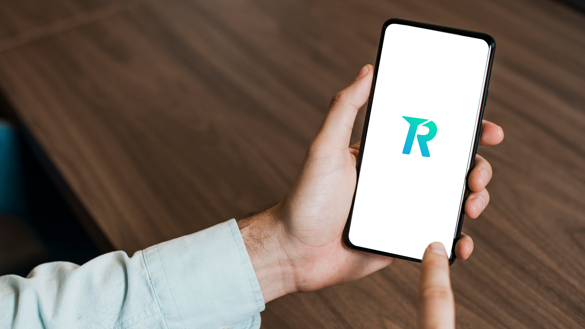 Tangan memegang smartphone yang menampilkan logo aplikasi Topremit untuk transfer uang ke luar negeri