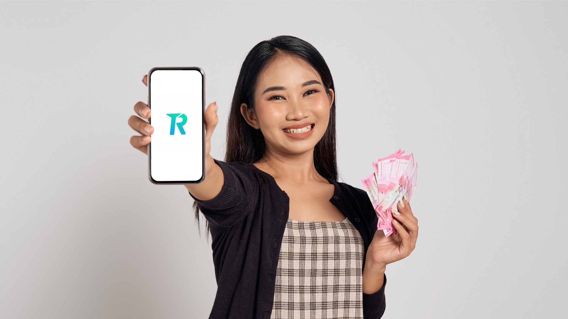 Pengguna menunjukkan aplikasi Topremit di smartphone sambil memegang uang tunai untuk kebutuhan transfer uang ke luar negeri