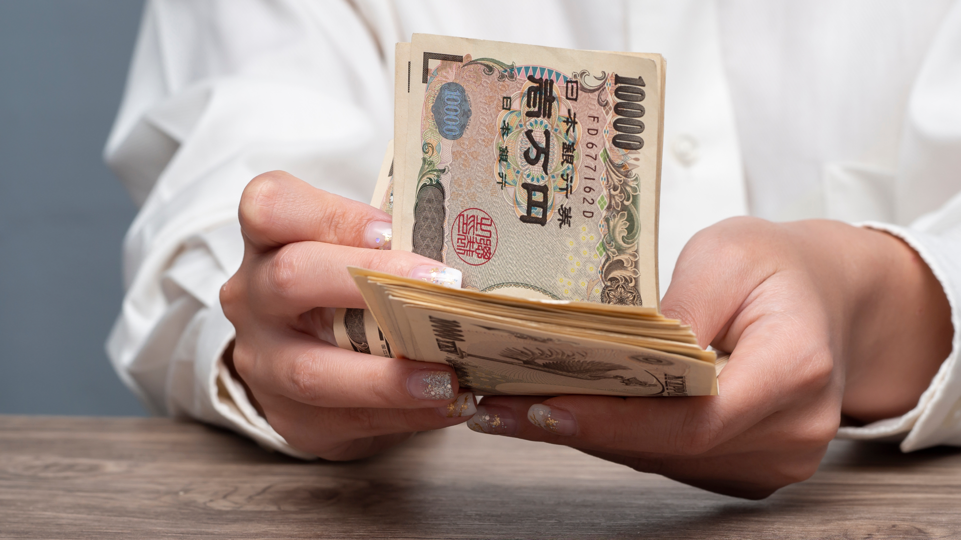 日本円の紙幣を数える様子。インドネシアから日本へ送金する際の受取額を確認するイメージ