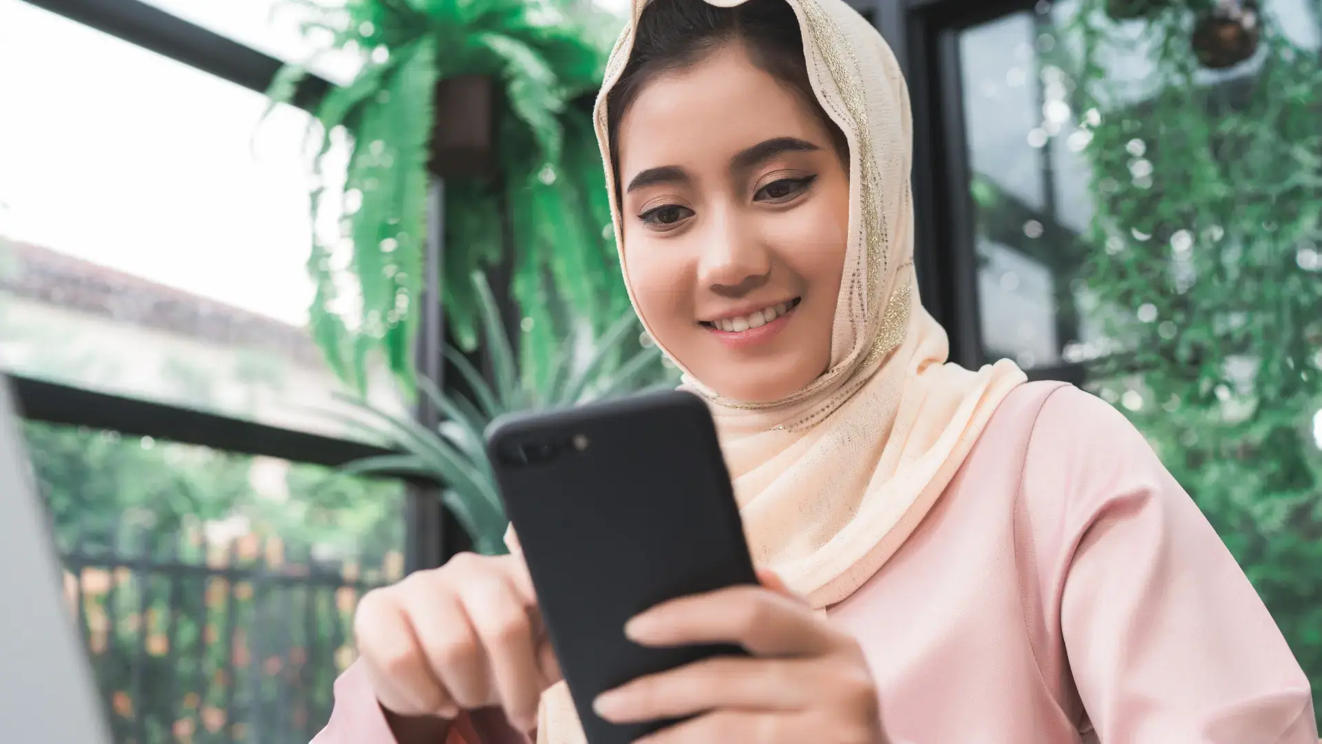 Wanita menggunakan smartphone untuk melakukan pembayaran biaya medis ke Malaysia