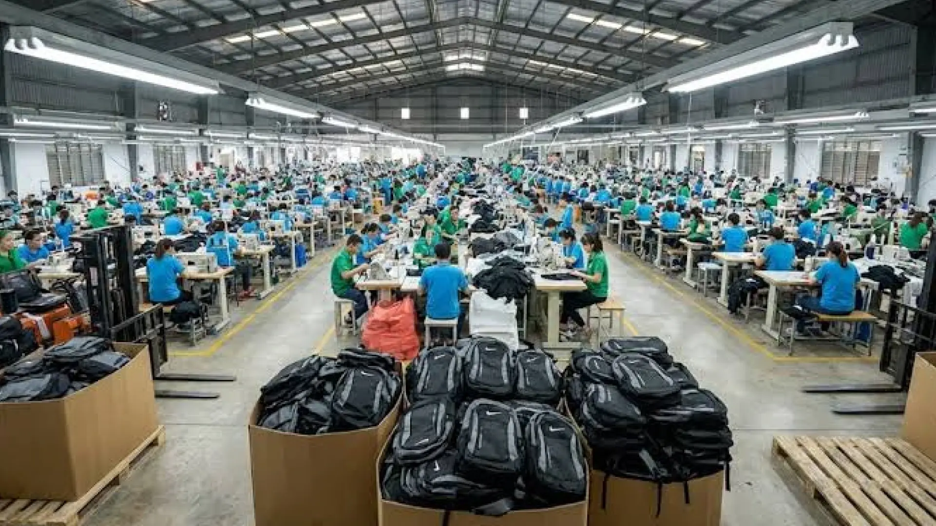 Aktivitas produksi tas di pabrik dengan ratusan pekerja dan tumpukan tas hitam siap dikemas.