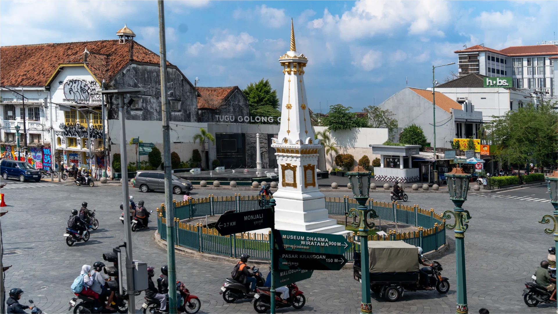 Yogyakarta 市中心的 Tugu Yogyakarta 纪念碑矗立在十字路口,周围是历史建筑和来往的车辆。
