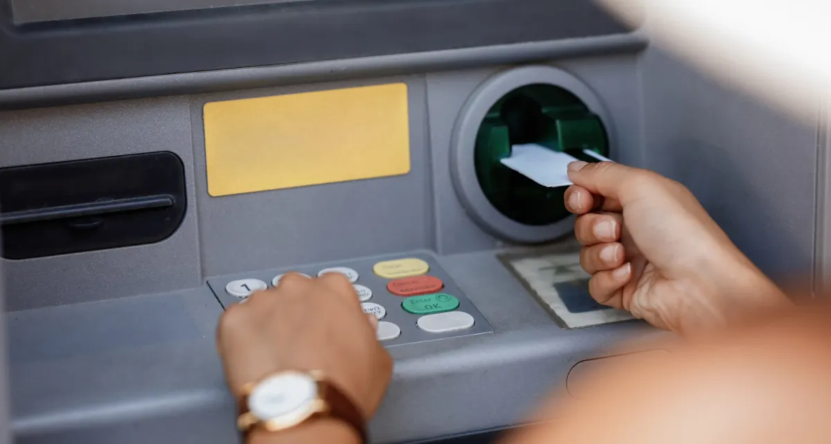 Seseorang sedang memasukkan kartu atm ke mesin atm untuk bertransaksi