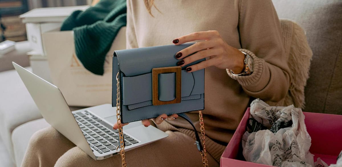 Perempuan memegang tas sambil memangku laptop
