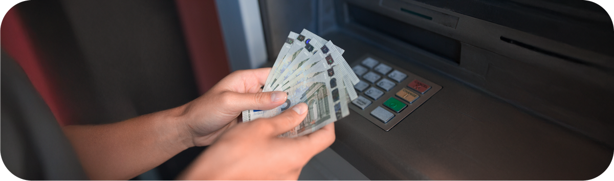 Seseorang sedang memegang uang dari mesin ATM.