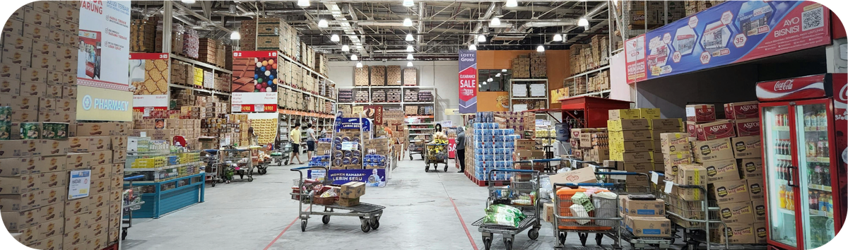Interior pusat belanja dengan rak tinggi berisi kardus dan berbagai produk impor.