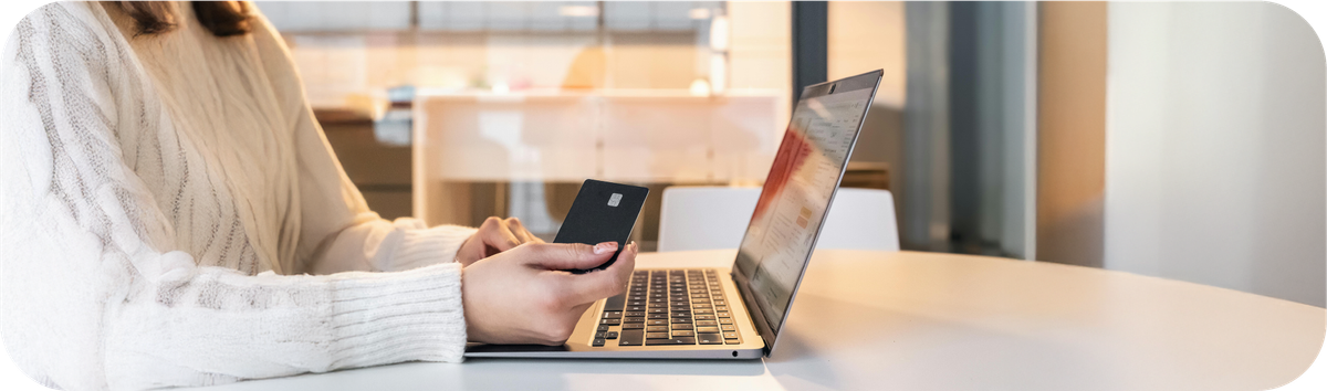 Seseorang melakukan pembayaran online menggunakan kartu bank di depan laptop untuk transaksi internasional.