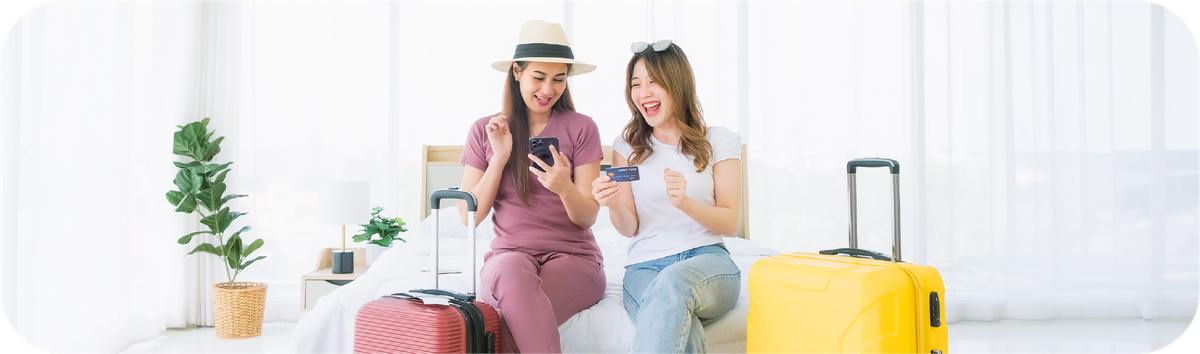 Dua wanita menggunakan smartphone dan kartu saat bepergian sebagai ilustrasi transfer uang ke luar negeri di hari libur.