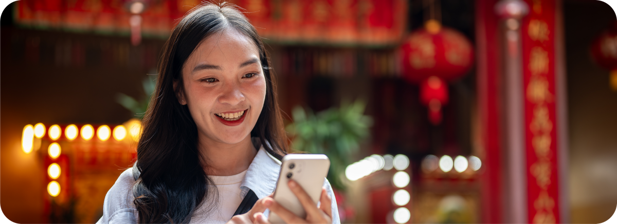 Seorang pengguna membuka smartphone di kawasan bernuansa China sebagai ilustrasi kemudahan kirim uang ke China.