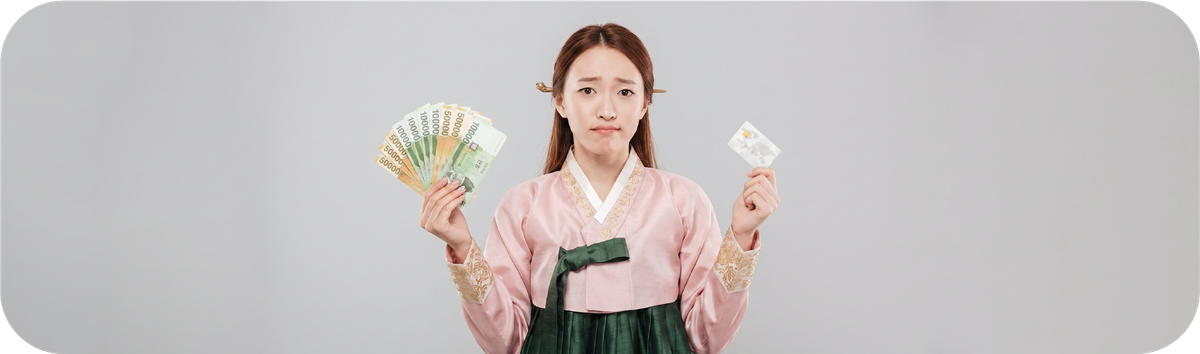 한국 전통 의상을 입은 여성이 원화와 카드를 들고 한국 송금 비용을 비교하는 모습