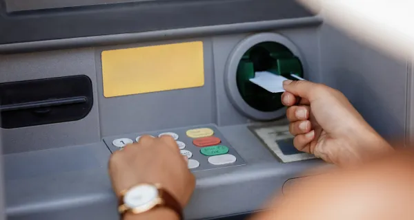 Seseorang sedang memasukkan kartu atm ke mesin atm untuk bertransaksi
