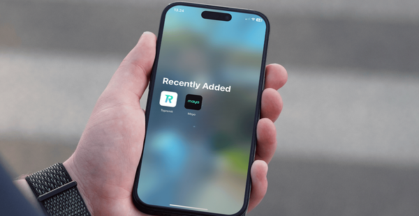 Hand holding phone with Topremit and Maya Wallet apps on screen