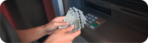 Seseorang sedang memegang uang dari mesin ATM.