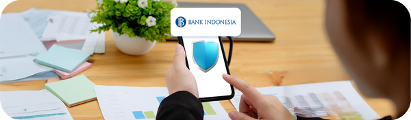 Ilustrasi keamanan transaksi keuangan digital dengan simbol perisai di layar ponsel dan logo Bank Indonesia, menandakan perlindungan dan kepatuhan regulasi.