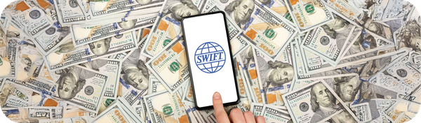 Sebuah smartphone dengan logo SWIFT di layar di atas tumpukan uang dolar AS yang melambangkan sistem pembayaran internasional.