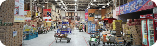 Interior pusat belanja dengan rak tinggi berisi kardus dan berbagai produk impor.