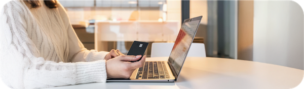 Seseorang melakukan pembayaran online menggunakan kartu bank di depan laptop untuk transaksi internasional.