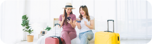 Dua wanita menggunakan smartphone dan kartu saat bepergian sebagai ilustrasi transfer uang ke luar negeri di hari libur.