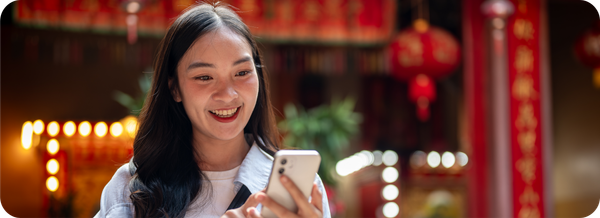 Seorang pengguna membuka smartphone di kawasan bernuansa China sebagai ilustrasi kemudahan kirim uang ke China.