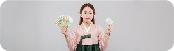한국 전통 의상을 입은 여성이 원화와 카드를 들고 한국 송금 비용을 비교하는 모습