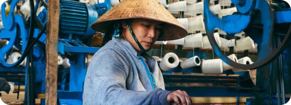 Pekerja mengoperasikan mesin tekstil di pabrik sebagai ilustrasi industri manufaktur Vietnam.